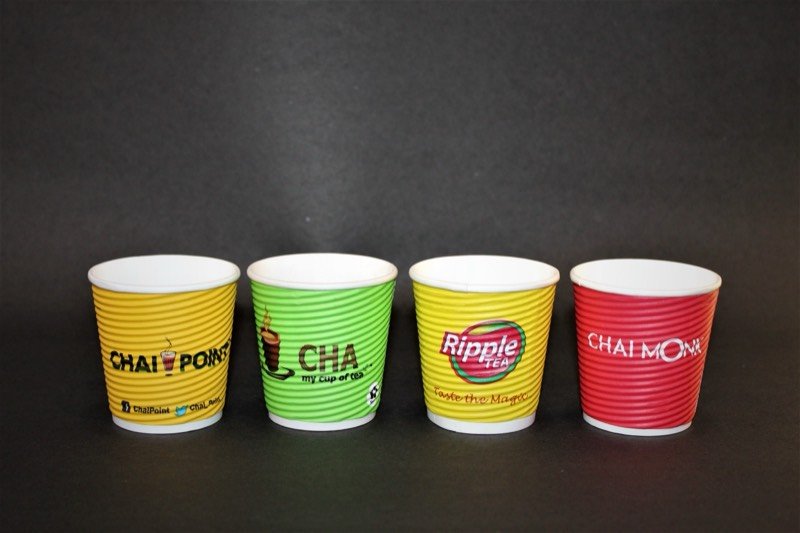 Four rippled paper cups printed for different Indian chai brands.